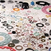 Diversas juntas, arandelas y piezas de diferentes materiales, tamaños y forma sobre fondo blanco.